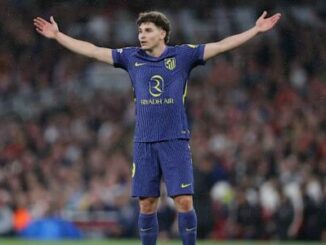 Footballeur bras écartés sur terrain de football
