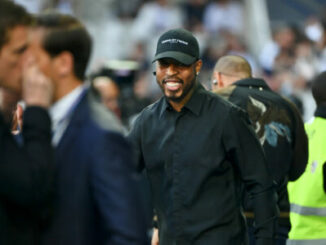 Homme souriant en casquette noire dans un stade