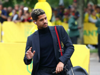 Homme en costume noir avec sac bandoulière rouge
