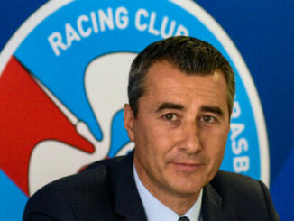 Homme en costume devant logo Racing Club
