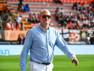 Homme en chemise bleue sur terrain de football