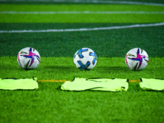 Trois ballons de football sur terrain vert
