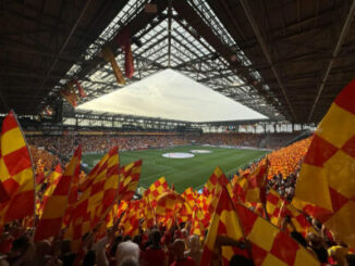 Stade rempli de supporters agitant drapeaux rouges et jaunes