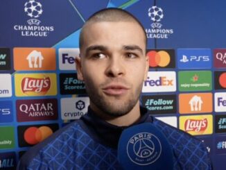 Footballeur interviewé devant panneau Ligue des champions