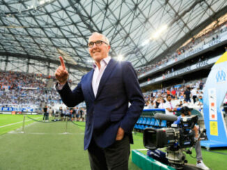 Homme en costume saluant dans un stade plein