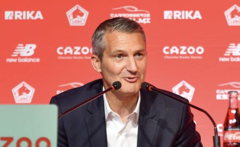 Homme en conférence de presse devant logos rouges