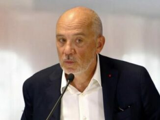 Homme chauve parlant devant un micro